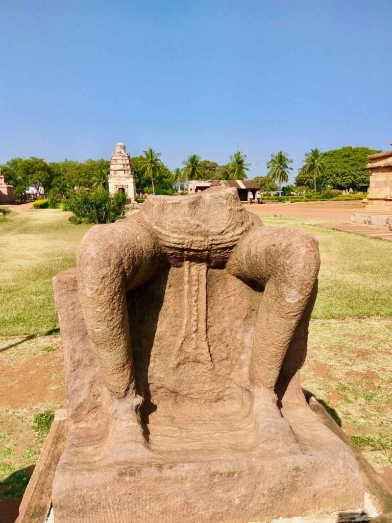 A big statue in the Aihole Museum, seated on a pedestal with the legs down (in bhadra-asana resembling the Maitreya statues and the Buddha statues of Ellora caves and Aurangabad caves), but its upper torso and head are lost. This is probably another Buddha statue.
